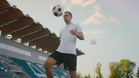 El-Jugador-De-Fútbol-Profesional-Está-Haciendo-Malabarismos-Con-Una-Pelota.-Socker-Un-Jugador-Con-Uniforme-De-Fútbol-Blanco-En-El-Estadio